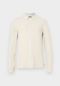 Langärmeliges Polohemd in hellem Beige mit strukturiertem Muster, Kragen und vorderer Knopfleiste. Weiches Material mit gerippten Bündchen.
