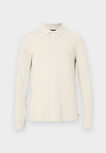 Langärmeliges Polohemd in hellem Beige mit strukturiertem Muster, Kragen und vorderer Knopfleiste. Weiches Material mit gerippten Bündchen.