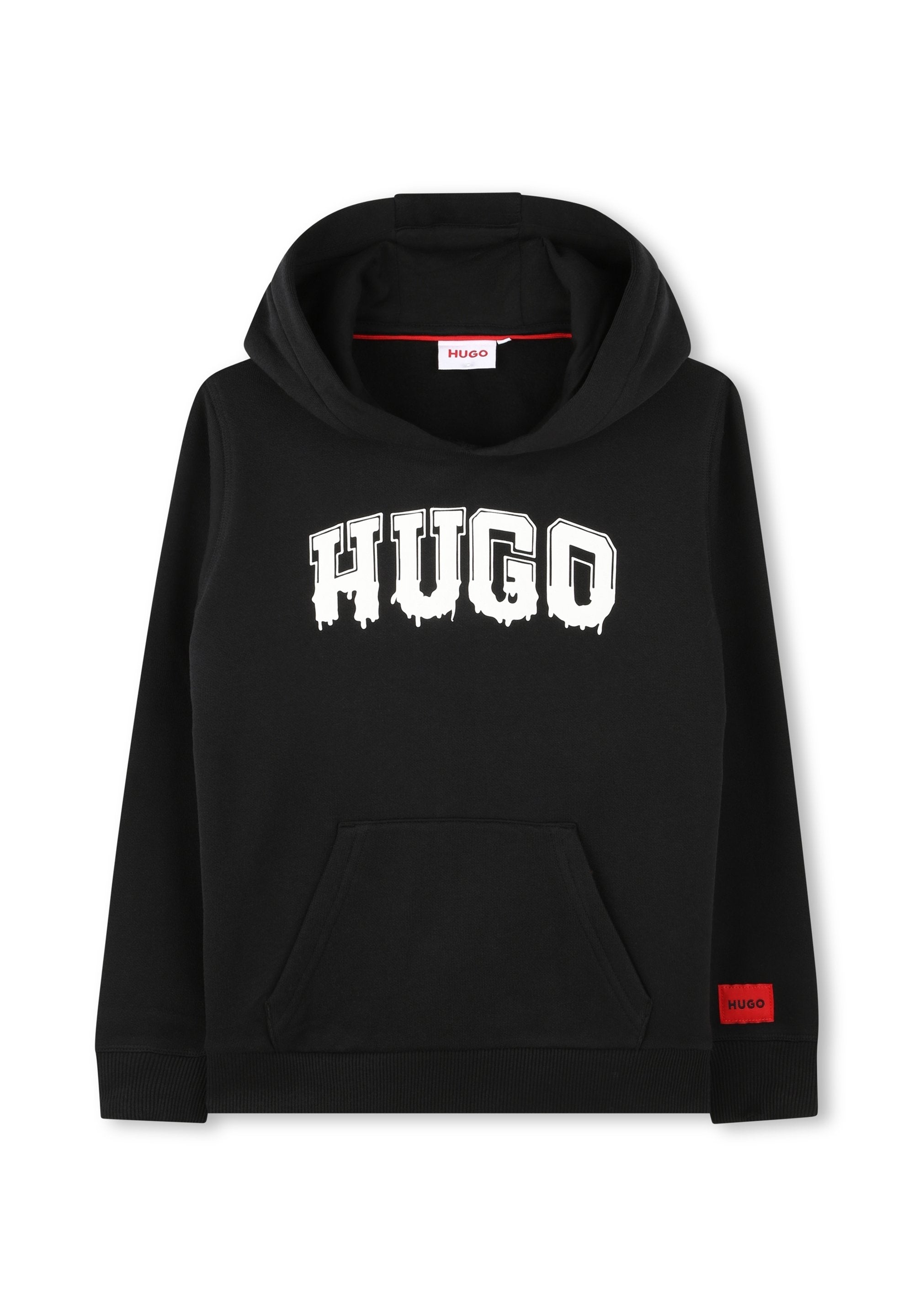 Schwarzer Hoodie aus Baumwollmischung, mit einem roten Logo-Etikett, geräumiger Fronttasche und auffälliger weißer "HUGO"-Schriftzug im Tropf-Style.
