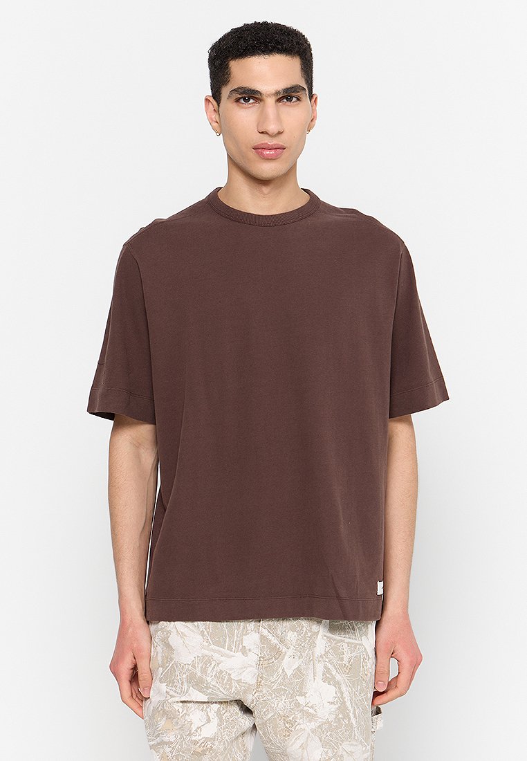 Braunes kurzärmliges T-Shirt aus weicher Baumwolle, mit Rundhalsausschnitt und lockerer Passform. Etikett auf der linken unteren Seite sichtbar.