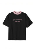 Schwarzes Kurzarm-T-Shirt mit hellrosa Kragen und rosa kursivem Text auf der Vorderseite, der lautet: „Du kannst deine Augen nicht von mir abwenden".