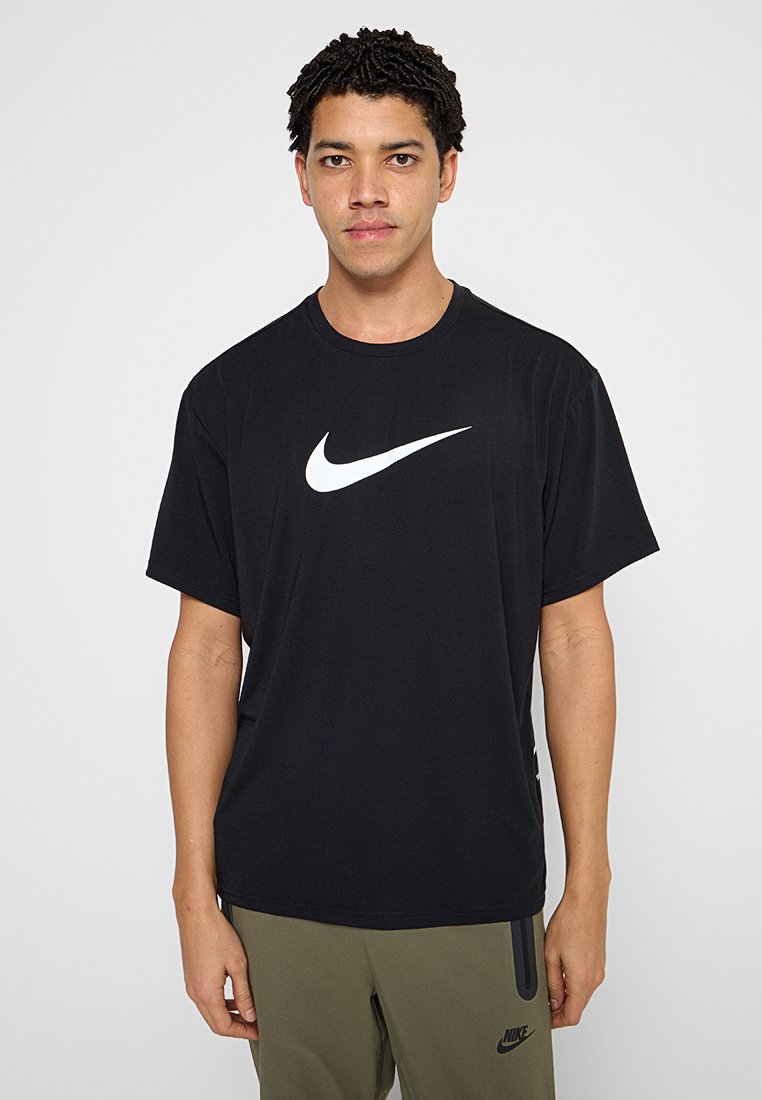 Schwarzes Baumwoll-T-Shirt mit einem großen weißen Nike-Swoosh-Logo auf der Brust. Lockerer Schnitt mit kurzen Ärmeln und rundem Ausschnitt.