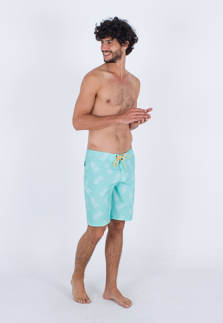 Türkise Badehose mit weißem Ananasmuster, Bindegürtel und Seitentasche. Aus leichtem Material, knielanger Schnitt.
