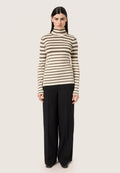 Gestreiftes Langarm-Turtleneck in Creme und Braun, figurbetonte Silhouette. Kombiniert mit schwarzen, weiten Hosen und spitzen, schwarzen Schuhen.