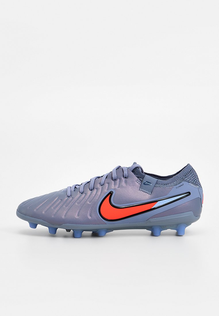 Nike-Fußballschuhe in Lila mit orangefarbenen Akzenten. Verfügen über ein strukturiertes Obermaterial, traditionelle Schnürung und eine geformte Sohle mit Stollen für besseren Halt.