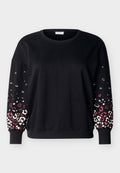 Schwarzer langärmeliger Pullover mit Rundhalsausschnitt und gerippten Bündchen, mit pink-weißem Leopardenmuster auf den unteren Ärmeln.