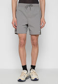 Graue, leichte Badeshorts mit einem elastischen Bund und Kordelzug. Seitentaschen und ein kleines Logo-Detail am Saum.