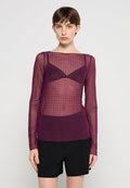 Durchsichtige lila Langarm-Bluse mit Punktmuster, über einem passenden Bralette getragen. Kombiniert mit schwarzen hochsitzienden Shorts.