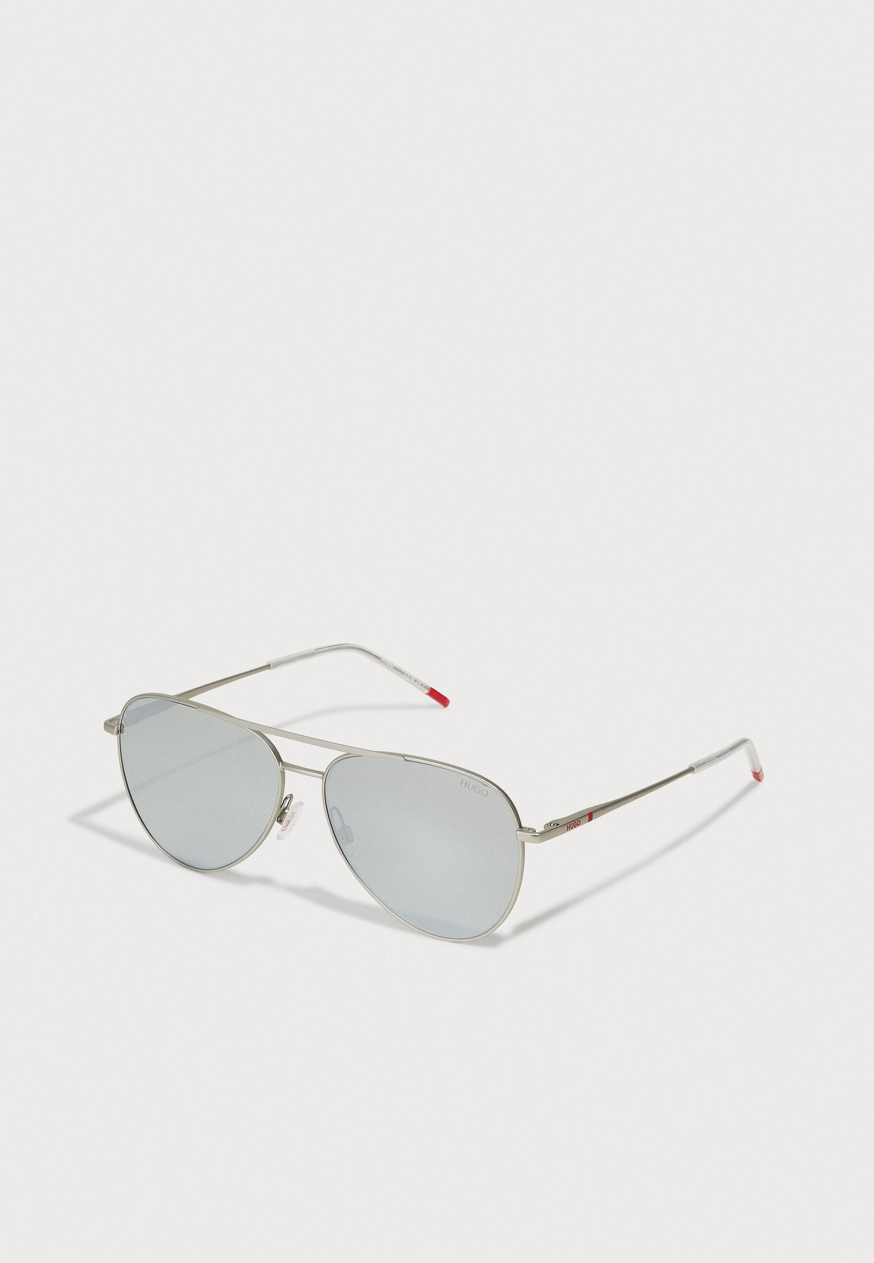 Silberne Metall-Aviator-Sonnenbrillen mit hellblauen Gläsern. Merkmale sind dünne Rahmen, Gummispitzen an den Bügeln und rote Akzente an den Schläfen.