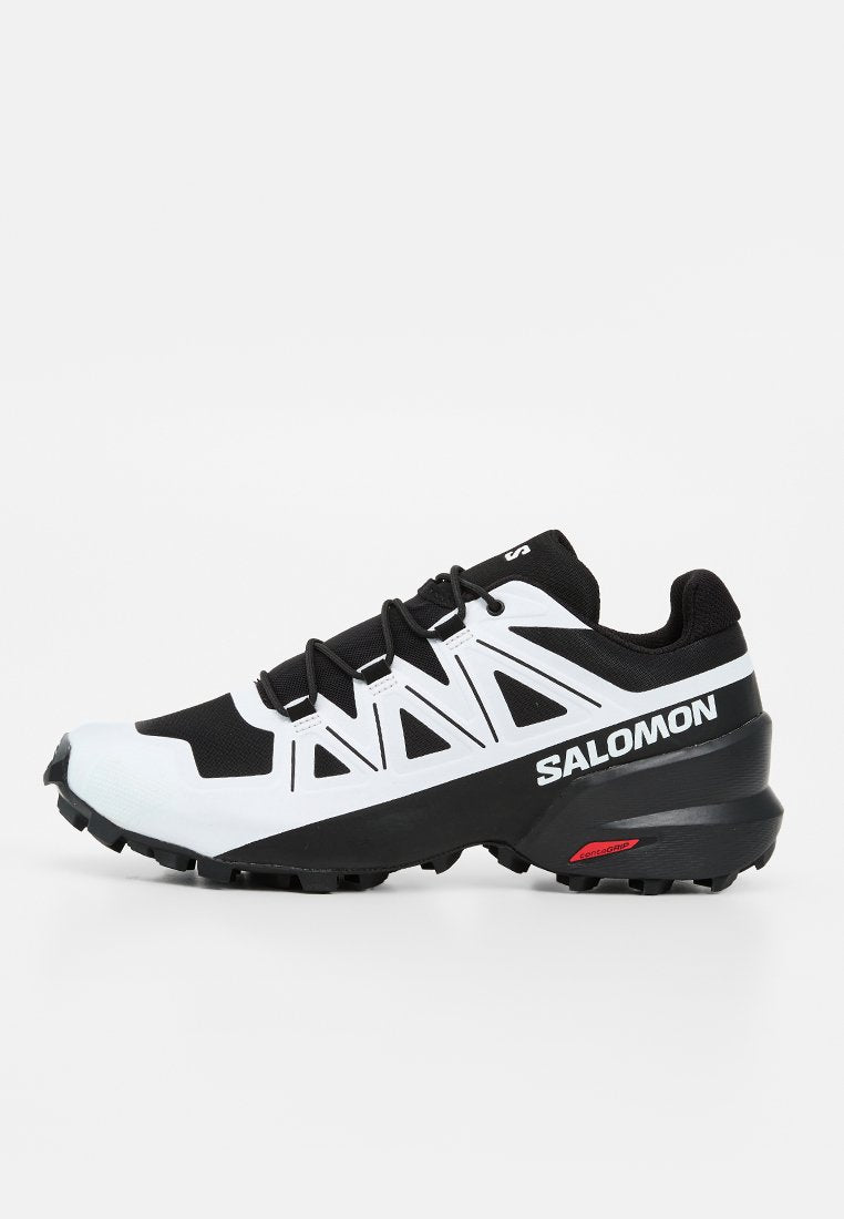 Schwarz-weißer Salomon Trailrunning-Schuh mit robuster Sohle und Markennamen an der Seite, entwickelt für Outdoor-Aktivitäten und guten Grip.