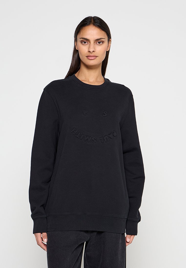 Schwarzer Pullover mit Rundhalsausschnitt, gerippten Bündchen und Saum. Strukturierter Smiley-Design und Schriftzug "CALL SMILE" auf der Vorderseite.