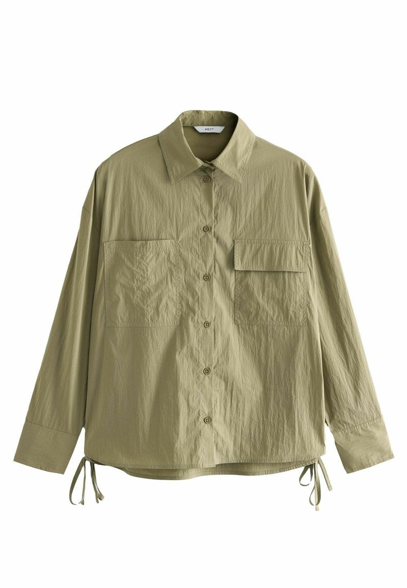 Helles olivgrünes Oversized-Hemd mit Knopfleiste, zwei vorderen Taschen und verstellbaren Bändern am Saum. Hergestellt aus einem strukturierten Material.