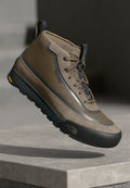 Braune hochgeschnittene Wanderschuhe aus strukturiertem Wildleder und Mesh-Obermaterial, mit grauen Akzenten und einer schwarzen Vibram-Sohle mit gelben Details.