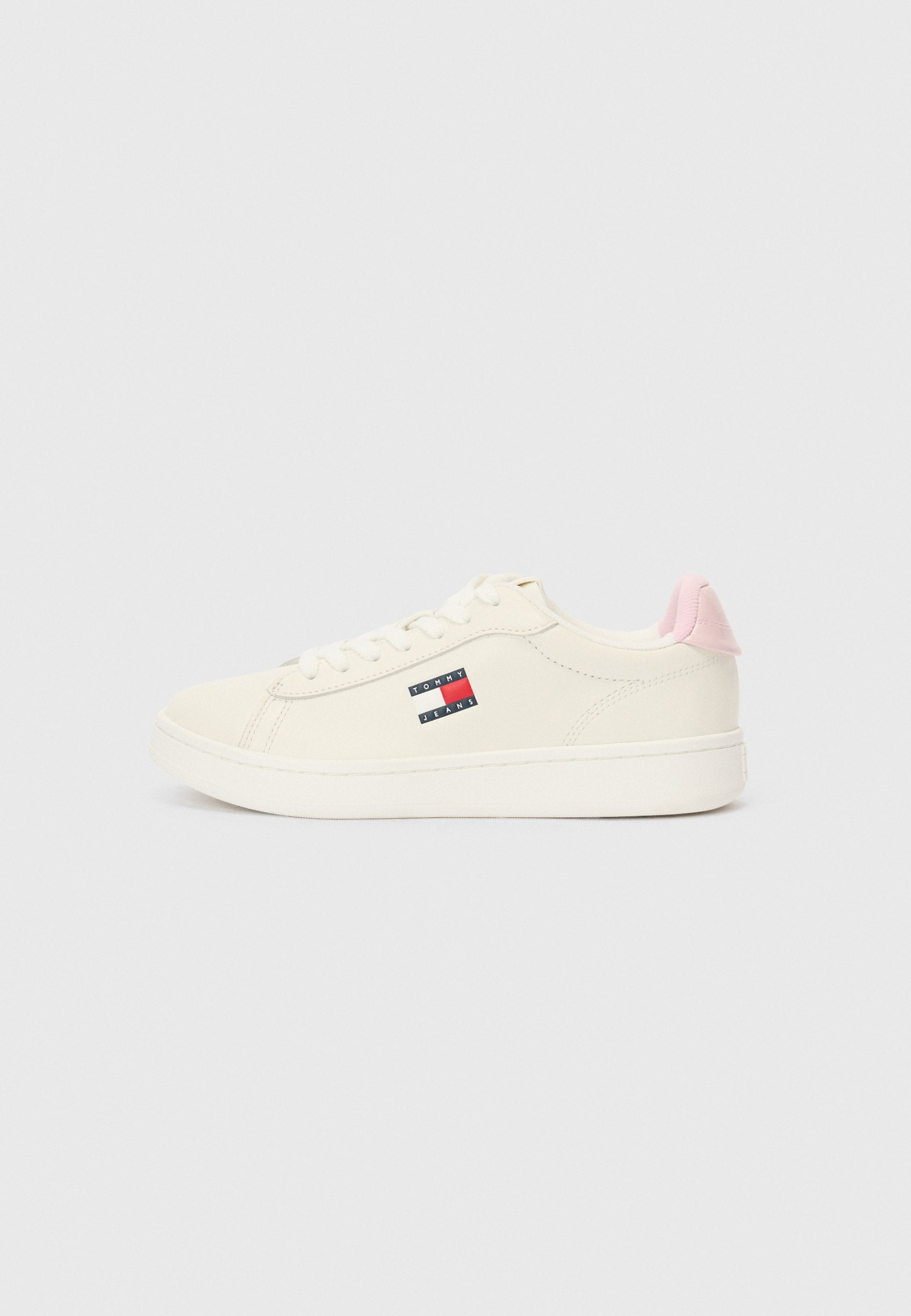 Weiße Low-Top-Sneaker mit pinkem Fersenteil, Schnürung auf der Vorderseite und Tommy Jeans-Logo an der Seite, fotografiert vor einem einfarbigen Hintergrund.
