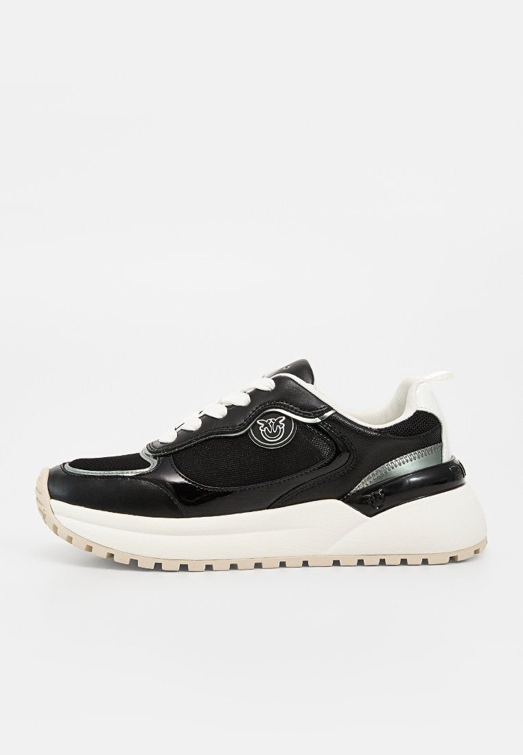 Schwarz-weißer Low-Top-Sneaker mit weißen Schnürsenkeln, dicker beiger Sohle, Mesh- und Leder-Obermaterial und rundem Logo auf dem seitlichen Panel.