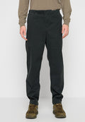 Schwarze Hosen mit elastischem Bund und lockerer Passform, mit Seitentaschen und einer glatten Stoffstruktur. Kombiniert mit braunen Schuhen.