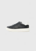 Schwarzer niedriger Sneaker mit weißen Schnürsenkeln, weißer Sohle und weißem Fersenlasche, im Seitenprofil vor einem hellgrauen Hintergrund gezeigt.