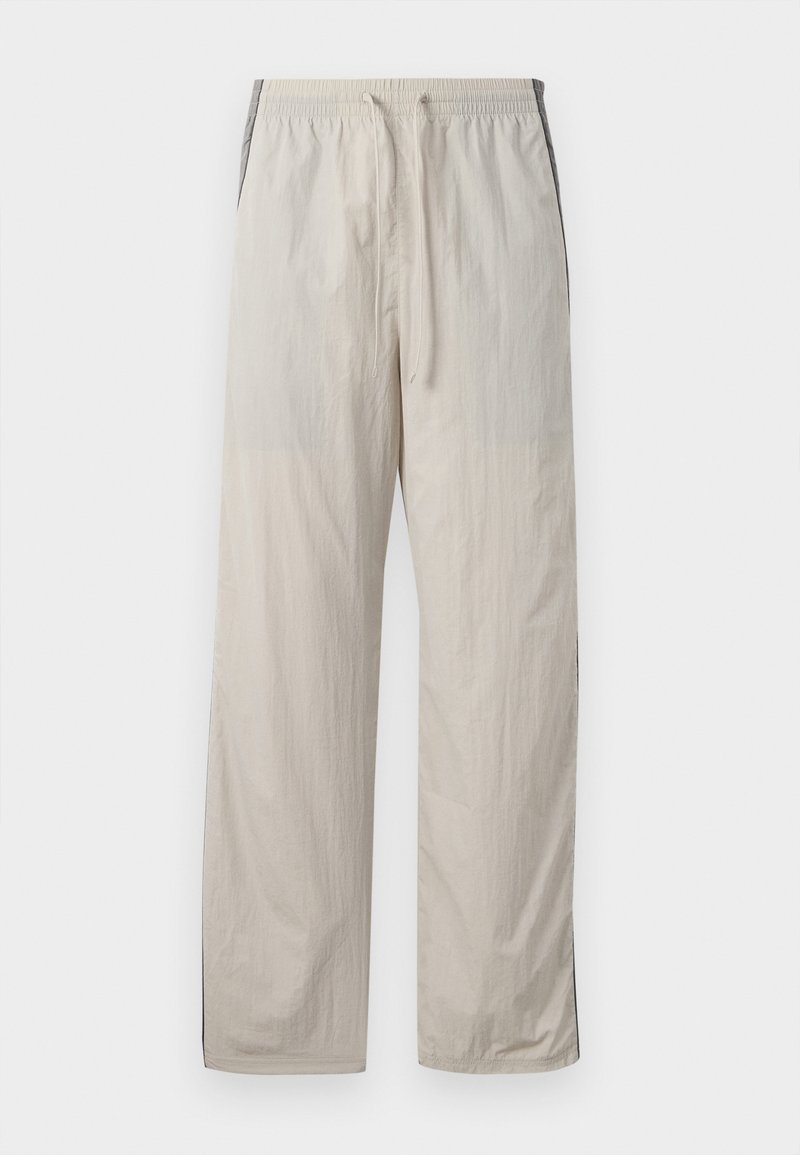 Beige, leichte Jogginghose mit Kordelzug und elastischem Bund, ausgestattet mit dunklen Seitenpaneelen und einem lockeren, geraden Bein-Design.