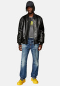 Schwarze Lederbomberjacke, graues Grafik-T-Shirt, blaue Denim-Jeans und gelbe Sneaker. Zubehör umfasst eine dunkle Kappe. Lässiges Outfit.