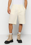 Mann in beigen, knielangen Shorts mit elastischem Bund, weißen Socken und beigen High-Top-Stiefeln mit schwarzen Sohlen.