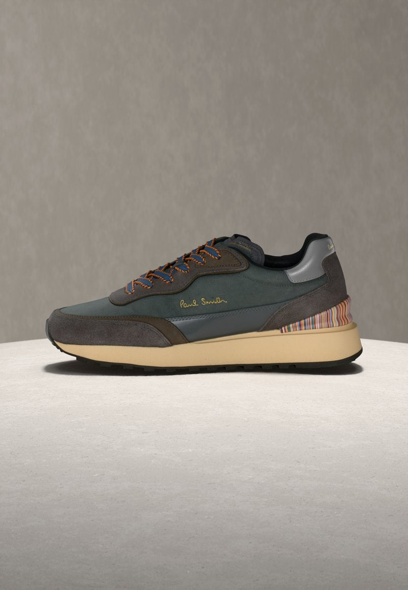Sneakers bestehen aus einer Kombination von dunkelgrünem und grauem Wildleder, mit orangen Schnürsenkeln, einem gut sichtbaren Logo und einem mehrfarbigen, gestreiften Fersen-Akzent.
