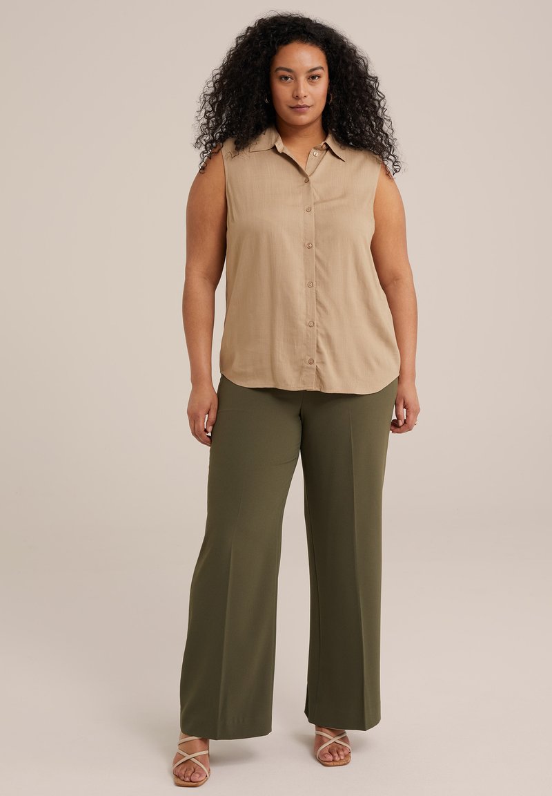 Tan ärmelloses Hemd mit Knöpfen, kombiniert mit olivgrünen weiten Hosen und nudefarbenen Sandalen mit Riemchen; glattes Material und lässige Passform.