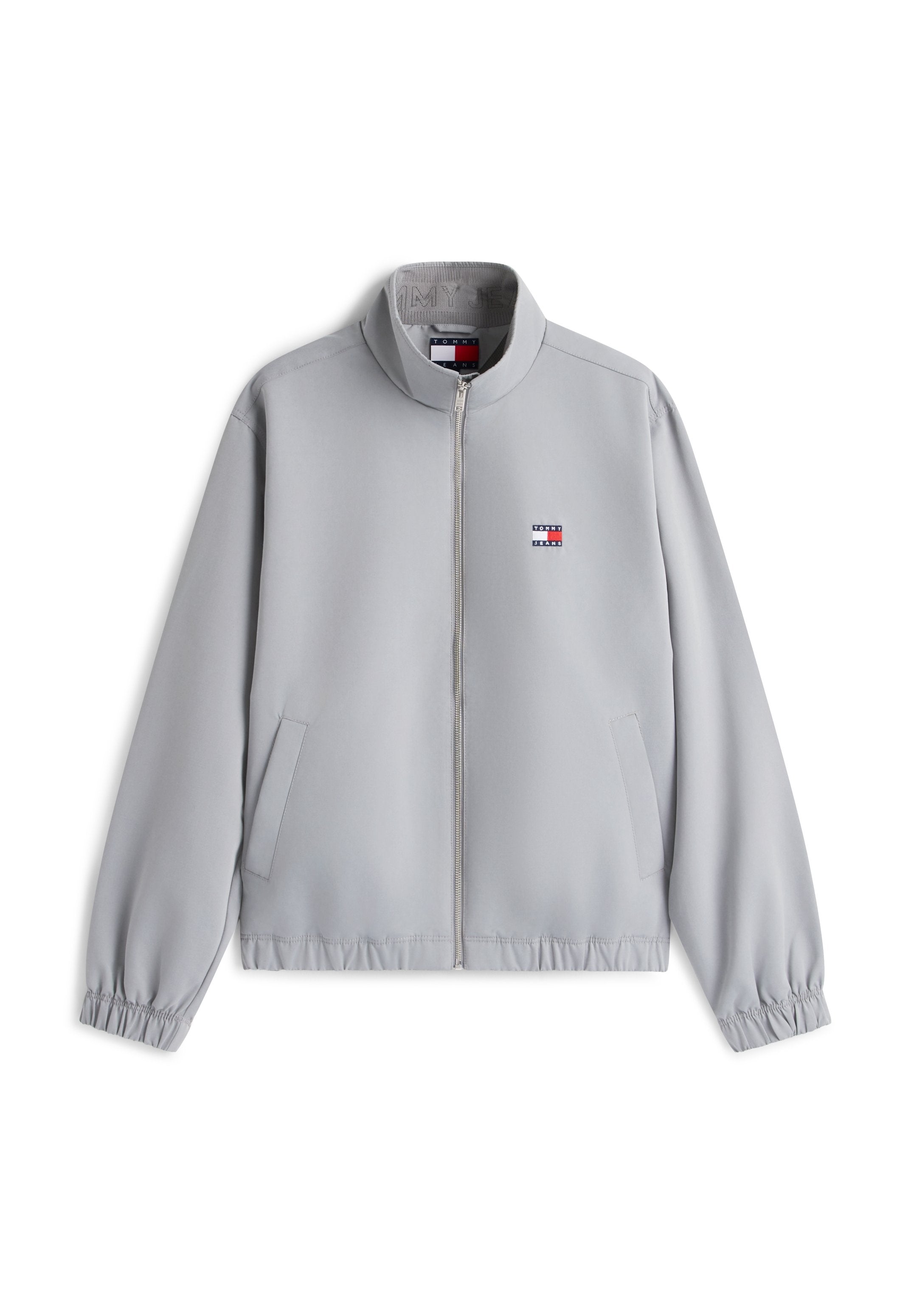 Hellgraue Reißverschlusstjacke mit Stehkragen, elastischen Bündchen und Saum, Seitentaschen sowie kleinem rot-weiß-blauem Logo auf der Brust.