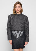 Gekürzte Jacke aus strukturiertem, dunkelgrauem Stoff mit einem Hahnentrittmuster, kombiniert mit einem schwarzen Rock, der ein weißes Herzdesign zeigt.