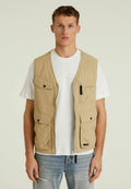 Beige Zip-Vest aus leichtem Stoff. Verfügt über mehrere Taschen, eine Brusttasche mit Reißverschluss und eine lässige Passform über einem weißen T-Shirt.