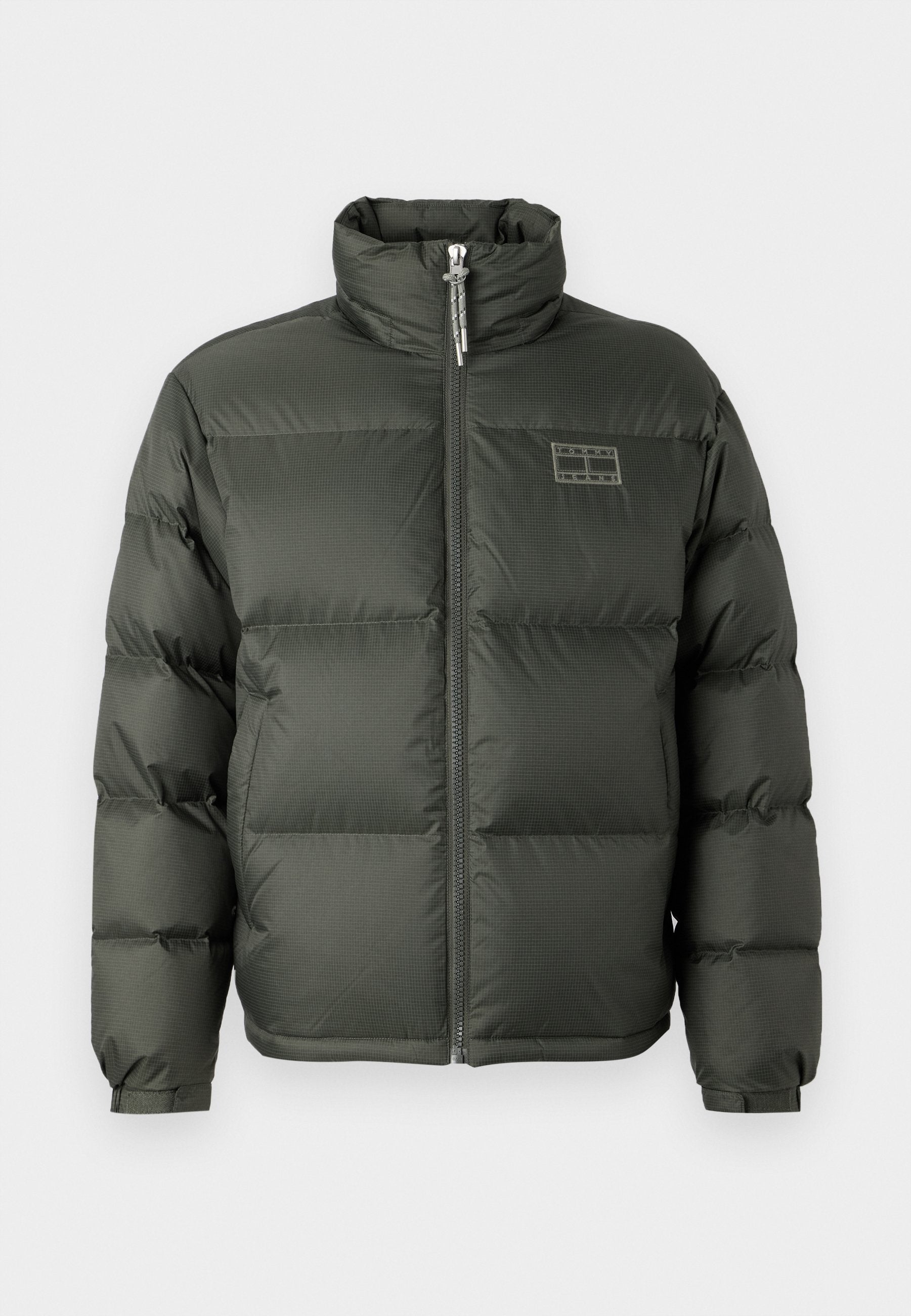 Grüne Puffjacke mit hohem Kragen, Frontreißverschluss, boxy Design und gesteppten Abschnitten. Mit einem kleinen Logodetail auf der oberen Brust.