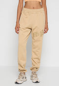 Beige Fleece-Jogginghosen mit gerippten Knöchelen, elastischem Bund, Seitentaschen und auffälligem Logo in einer dunkleren Nuance am Oberschenkel.