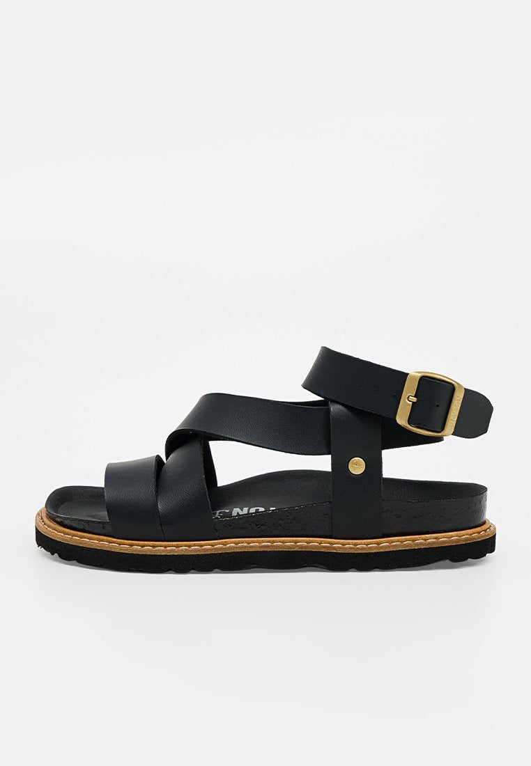Schwarze Ledersandale mit überkreuzten Riemen, goldener Schnalle am Knöchelriemen, beigen Nähten und schwarzer strukturierter Sohle.