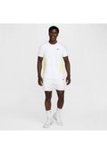 Männliches Sportoutfit mit einem weißen T-Shirt, das helle gelbe Seitenpanels und ein schwarzes Logo hat, ergänzt durch weiße Shorts und Socken.