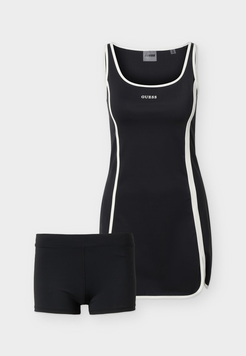 Schwarzes ärmelloses Badeanzugkleid mit weißem Rand und "GUESS"-Logo, kombiniert mit passenden schwarzen Badeshorts.