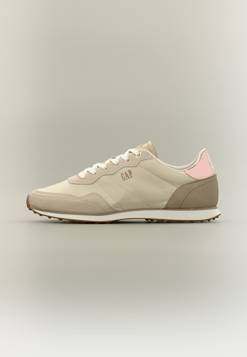 Beige und hellbrauer Freizeitschuh mit weißen Schnürsenkeln, pinkfarbenem Fersendetail und GAP-Logo an der Seite auf neutralem Hintergrund.
