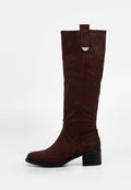 Brauner kniehoher Stiefel aus Wildleder mit niedrigem Blockabsatz, abgerundetem Zehenbereich und dekorativem Riemen mit Metalldetail nahe dem oberen Rand.