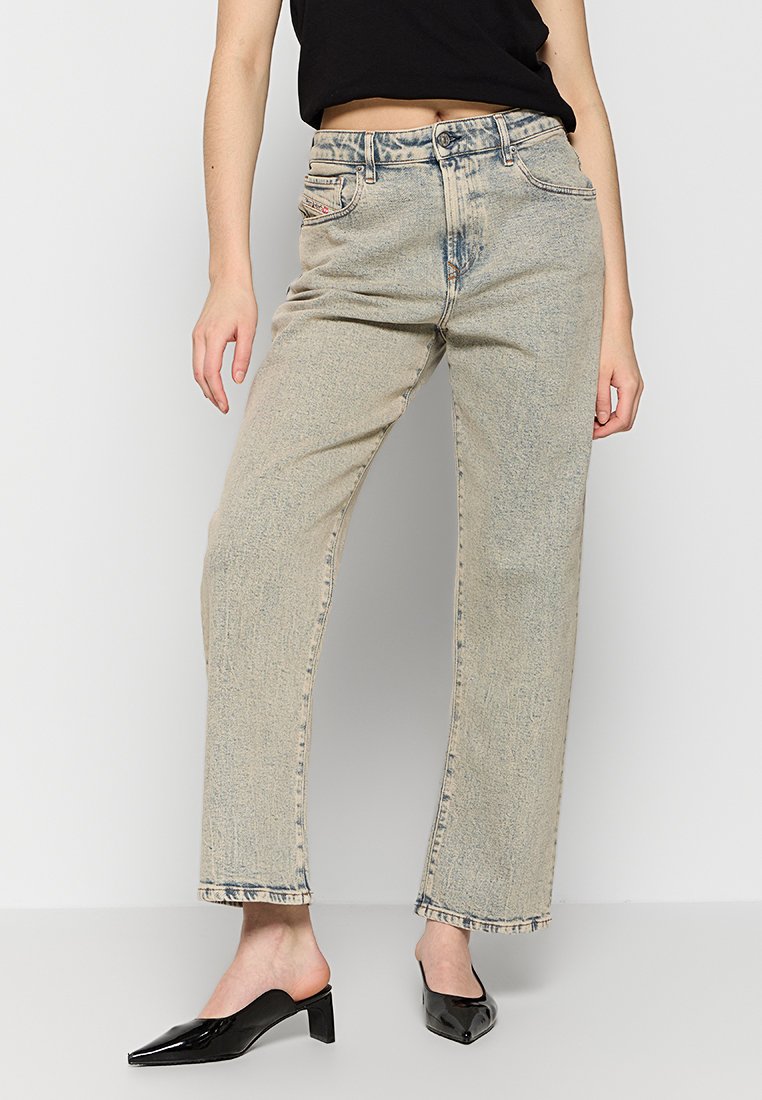 Hellblaue High-Waist-Jeans mit geradem Bein, verwaschenem Look, Fünf-Taschen-Design und Gürtelschlaufen, kombiniert mit schwarzen spitzen Slippern.