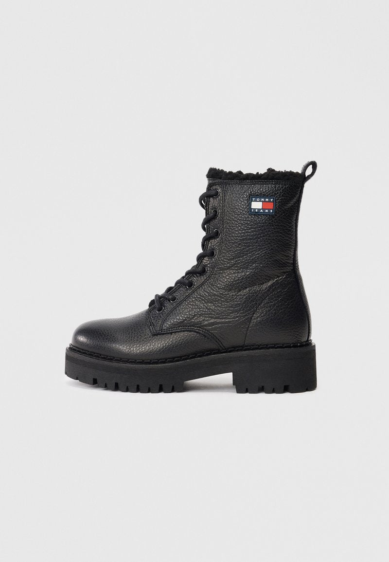 Schwarzer Leder Schnürstiefelette mit strukturiertem Finish, massiver Sohle und einer Kunstfellmanschette. Mit einem Logo-Patch an der Seite.