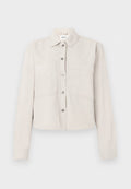 Hellbeige, kurz geschnittene Jacke mit langen Ärmeln, silbernen Druckknöpfen vorne, spitzem Kragen und zwei Brusttaschen.