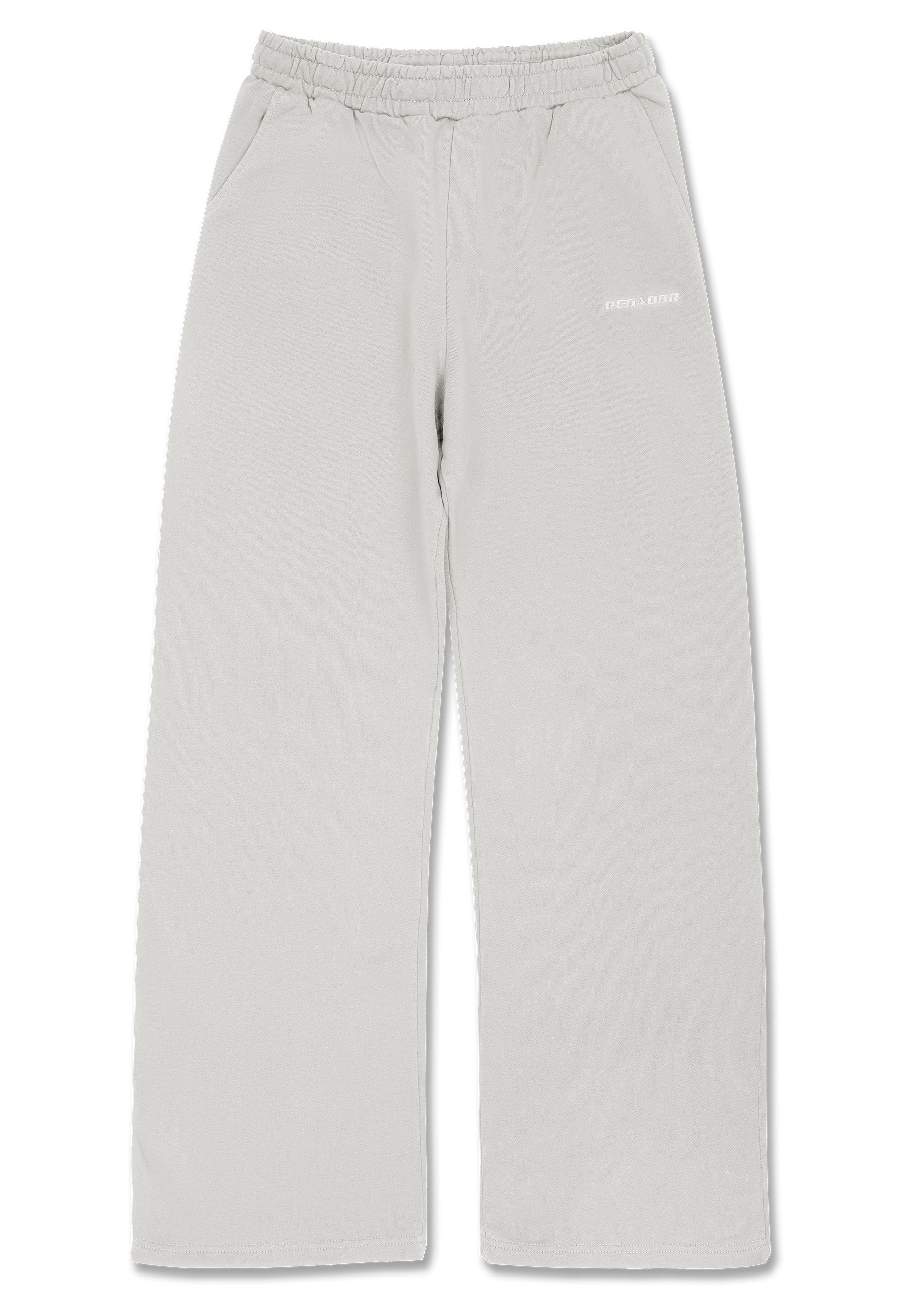 Hellgraue Jogginghose mit elastischem Bund, seitlichen Taschen, geraden Beinen und einem kleinen weißen Logo am linken Oberschenkel. Weiche Stoffstruktur.