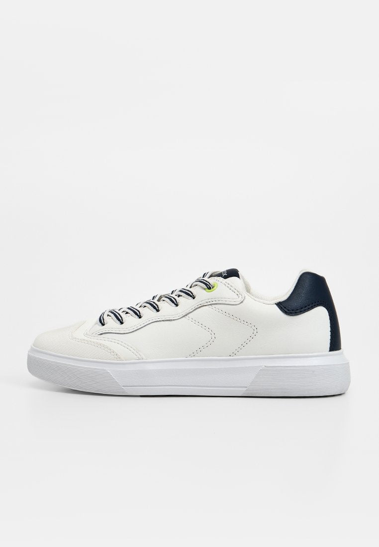 Weißer Low-Top-Sneaker mit navyfarbenem Fersenlasche, schwarz-weiß gestreiften Schnürsenkeln und einer dicken weißen Sohle vor einem einfarbigen Hintergrund.