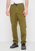 Olivengrüne, leichte Hose mit elastischem Bund, Kordelzug und zwei seitlichen Taschen, kombiniert mit dunklem Schuhwerk.