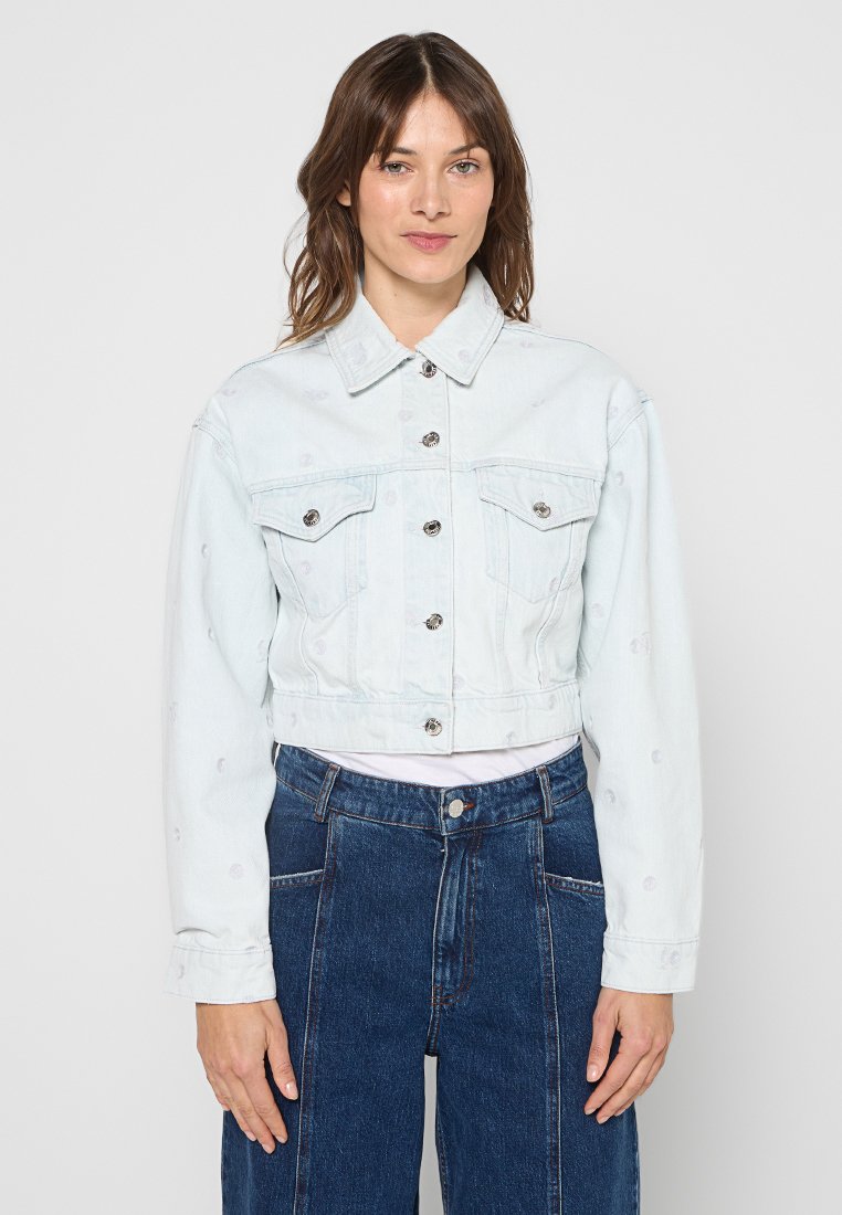 Hellblaue kurze Jeansjacke mit langen Ärmeln, durchgehender Knopfleiste vorne und zwei Brusttaschen mit silbernen Beschlägen. Glatte Textur.