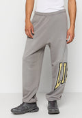 Graue Jogginghose mit einem elastischen Bund und dem Wort "LÜGE" in Gelb am linken Bein. Hergestellt aus weichem Stoff, mit lockerer Passform.