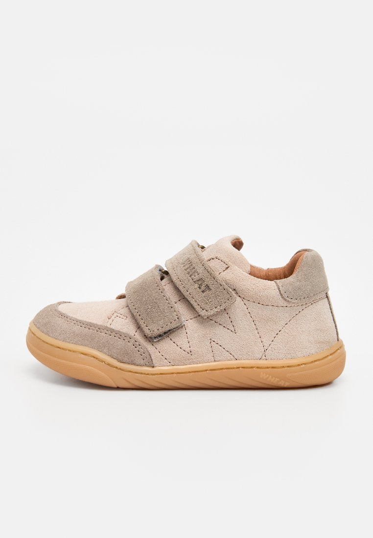 Beiger Wildleder-Kinderschuh mit zwei Klettverschlüssen und einer Laufsohle aus Kaugummigummi, seitlich auf weißem Hintergrund gezeigt.
