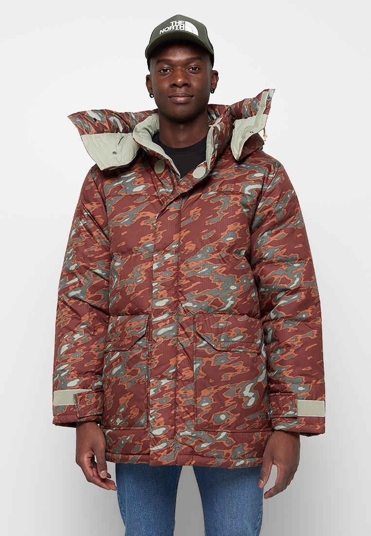 Rote und grüne Camouflage-Puffermantel mit hohem Kragen, verstellbare Kapuze und zwei Fronttaschen; strukturierter Stoff und strapazierfähige Nähte.