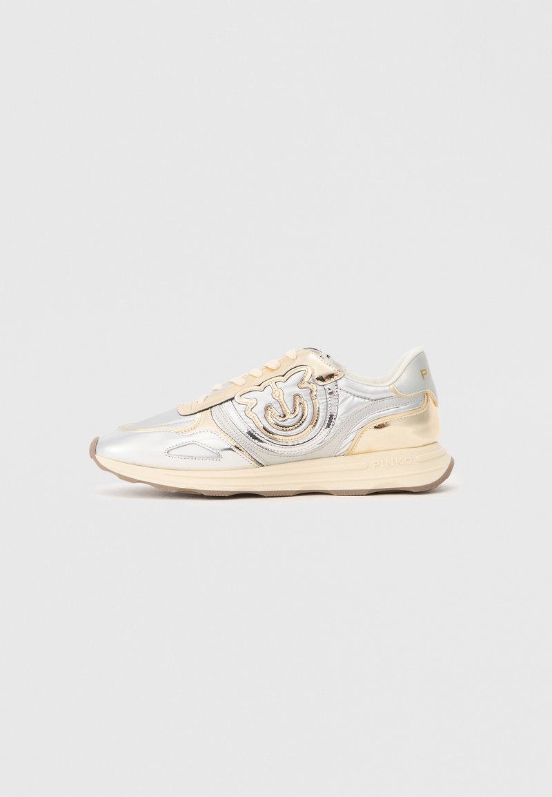 Metallisch silberner und beiger Sneaker mit runder Form, der ein auffälliges Logo, Schnürsenkel und strukturierte Akzente an den Seiten aufweist.