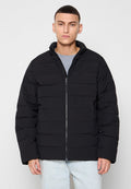 Schwarze Pufferjacke mit horizontalen Nähten, Reißverschluss vorne, hohem Kragen und langen Ärmeln. Getragen über einem grauen T-Shirt. Glatte Textur.