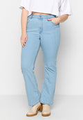 Hellblaue Jeans im Schlagstil mit hoher Taille, ausgestattet mit einem Reißverschluss, seitlichen Taschen und dezenten Nähdetails. Kombiniert mit beigen Stiefeletten.