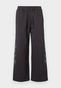 Schwarze, weit geschnittene Sweatpants mit elastischem Bund, verziert mit einem grauen Flammendesign an der Seite, akzentuiert mit kleinen Strasssteinen.